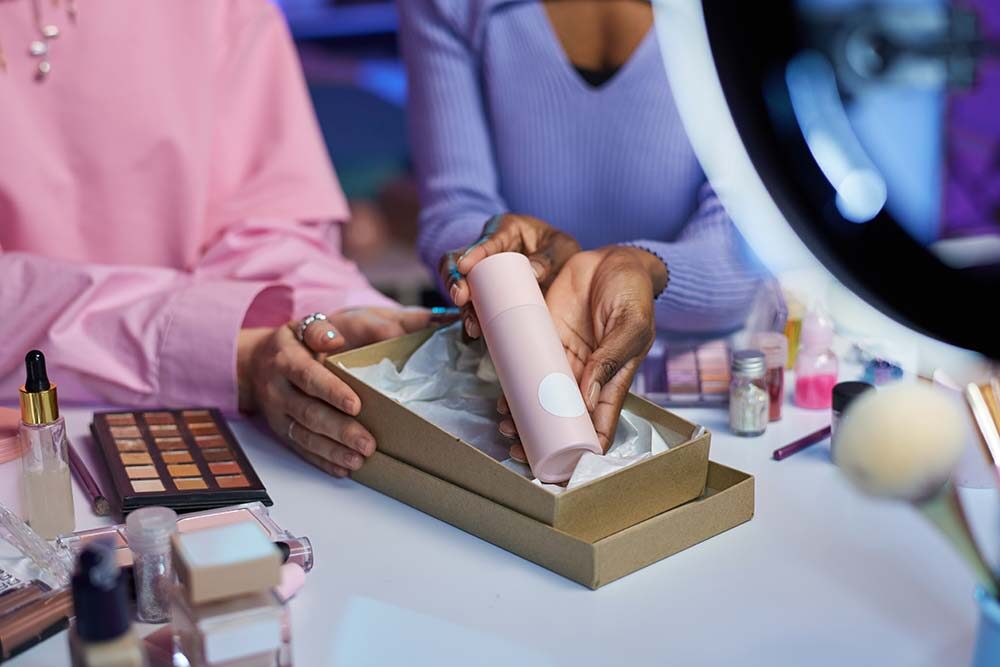 Hands unboxing a pink cosmetic bottle from a branded box, highlighting unboxing experience in beauty product packaging